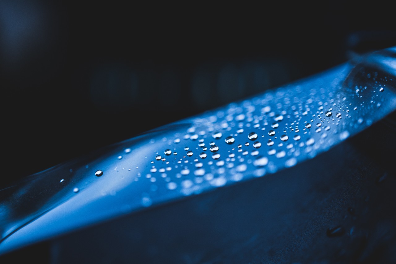 Macro shot of water drops on a thin film. Hydrophobic effect. Water-repellent or Water-resistant Concept. High Resolution Photography.