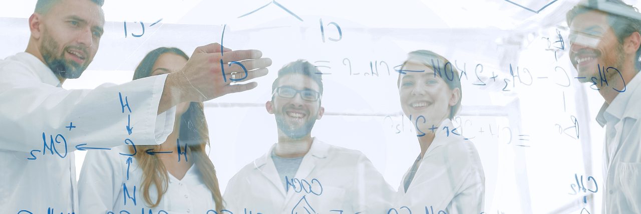 group of laboratory scientists discussing their research in the