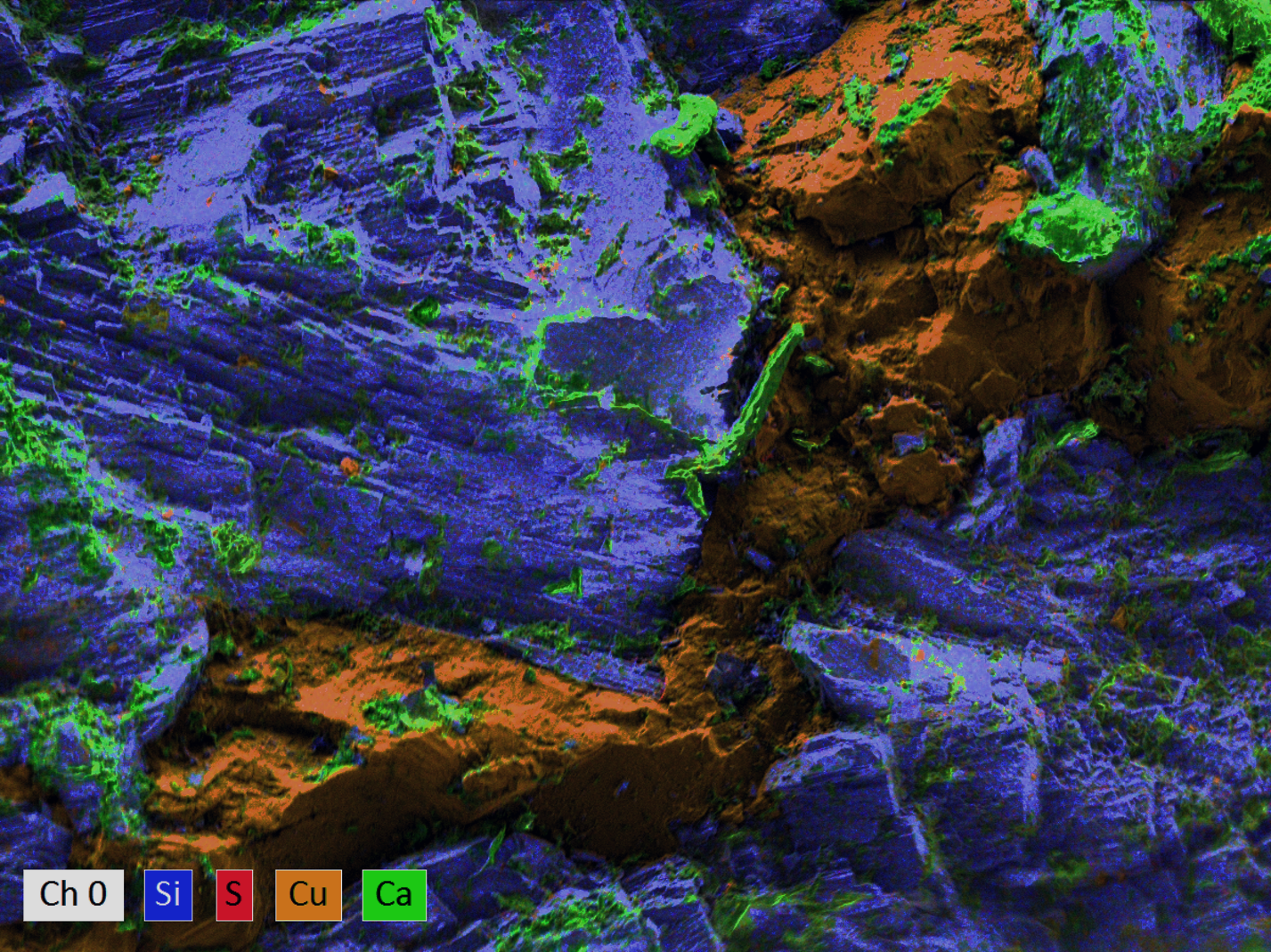 elemental map of textured mineral surface. The bulk of material is silicon (blue) and calcium (green) with a vein of  copper (yellow) running through the center, which contains some small regions of calcium