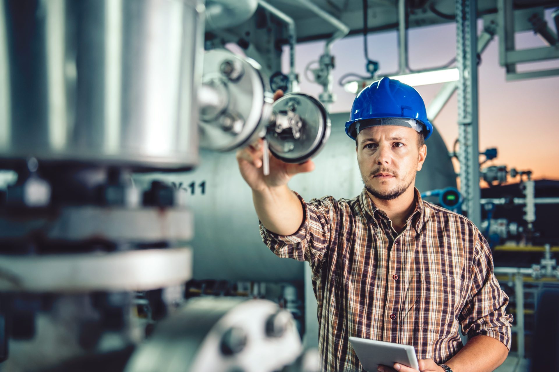 Man wearing blue hardhat using tablet at a gas processing facility