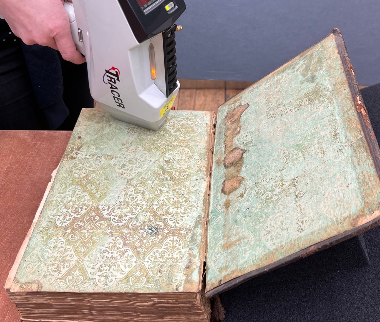 Handheld XRF system being used to scan the inside page of a victorian-era book to determine if toxic pigments were used.