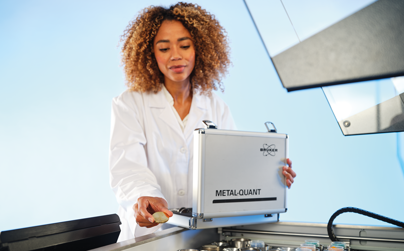 Image showing a woman using pre-made calibration for metal elemental analysis. The woman is inserting the calibration disk into the WDXRF spectrometer