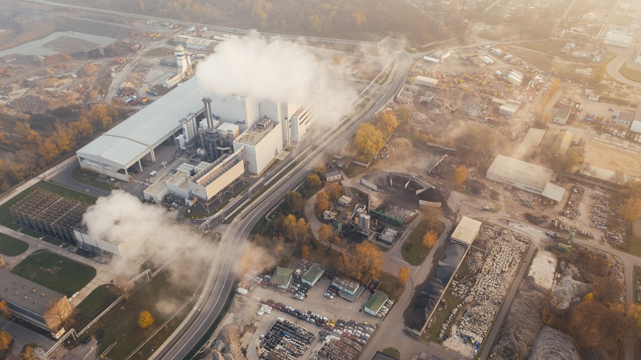 Industrial landscape with chimneys from which clouds of smoke are billowing out.